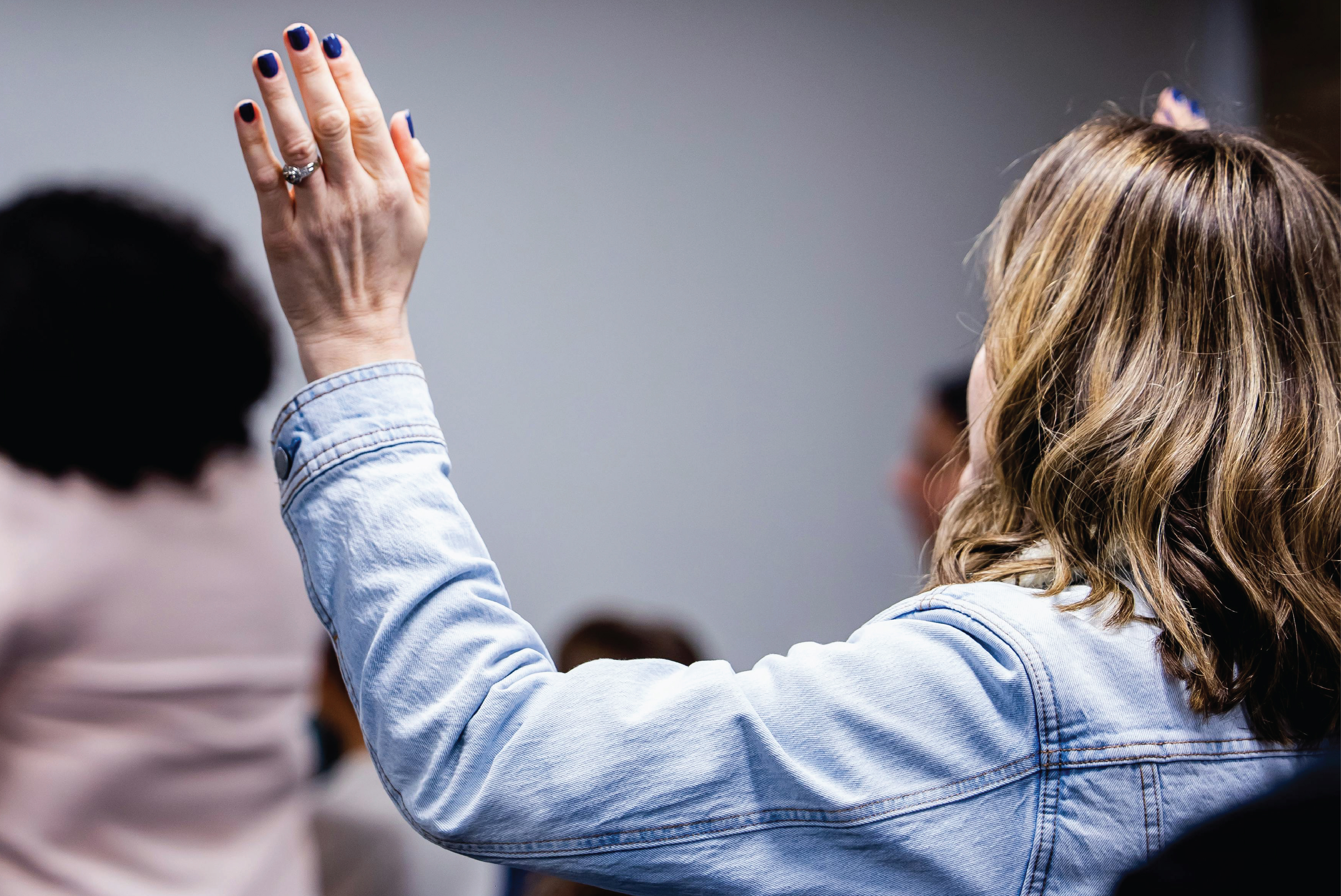 Woman raising her hand to ask a question
