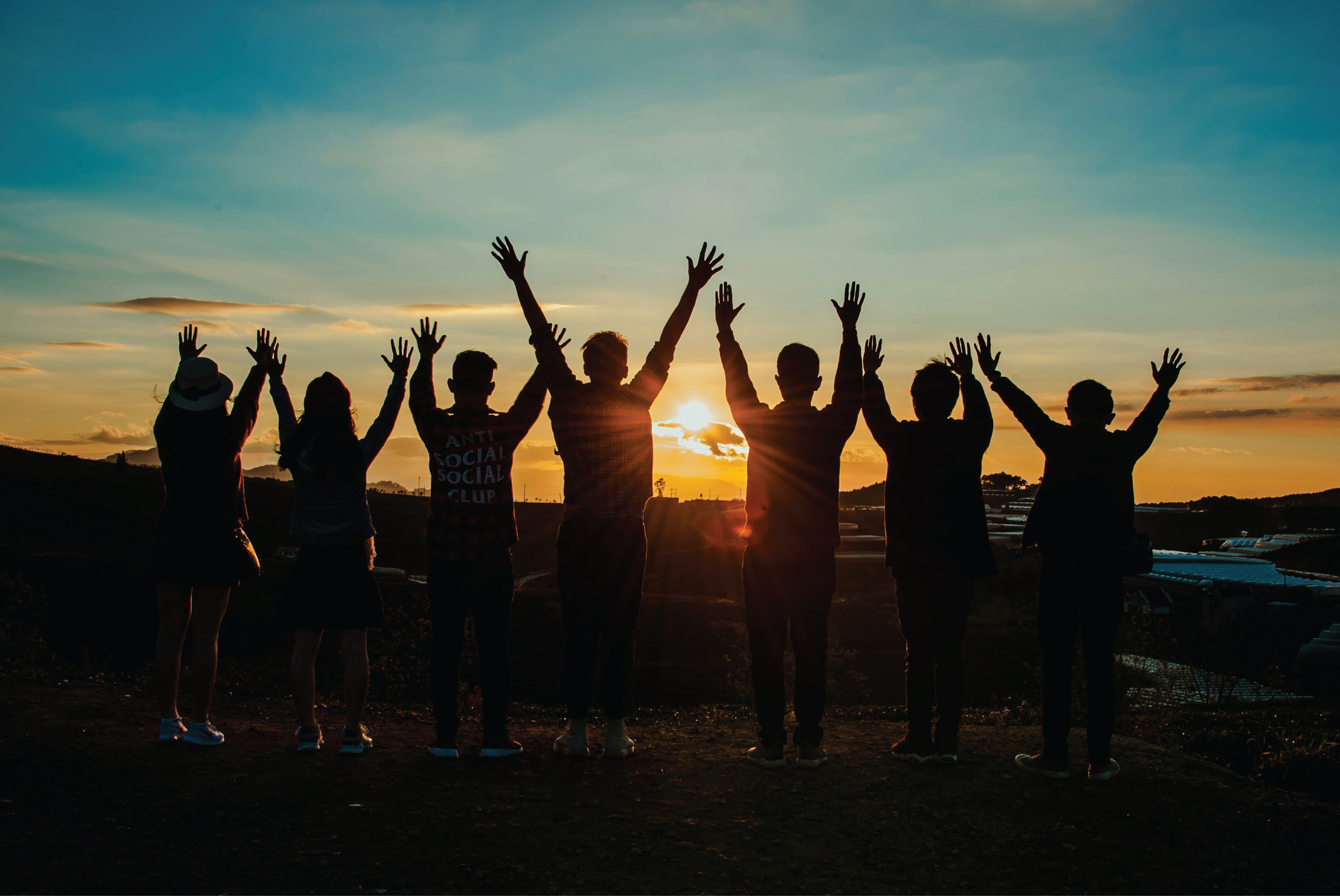 Group of people facing a sunset